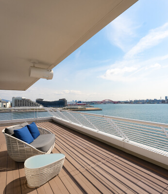 写真：ソファがあるバルコニーと昼の港の景色